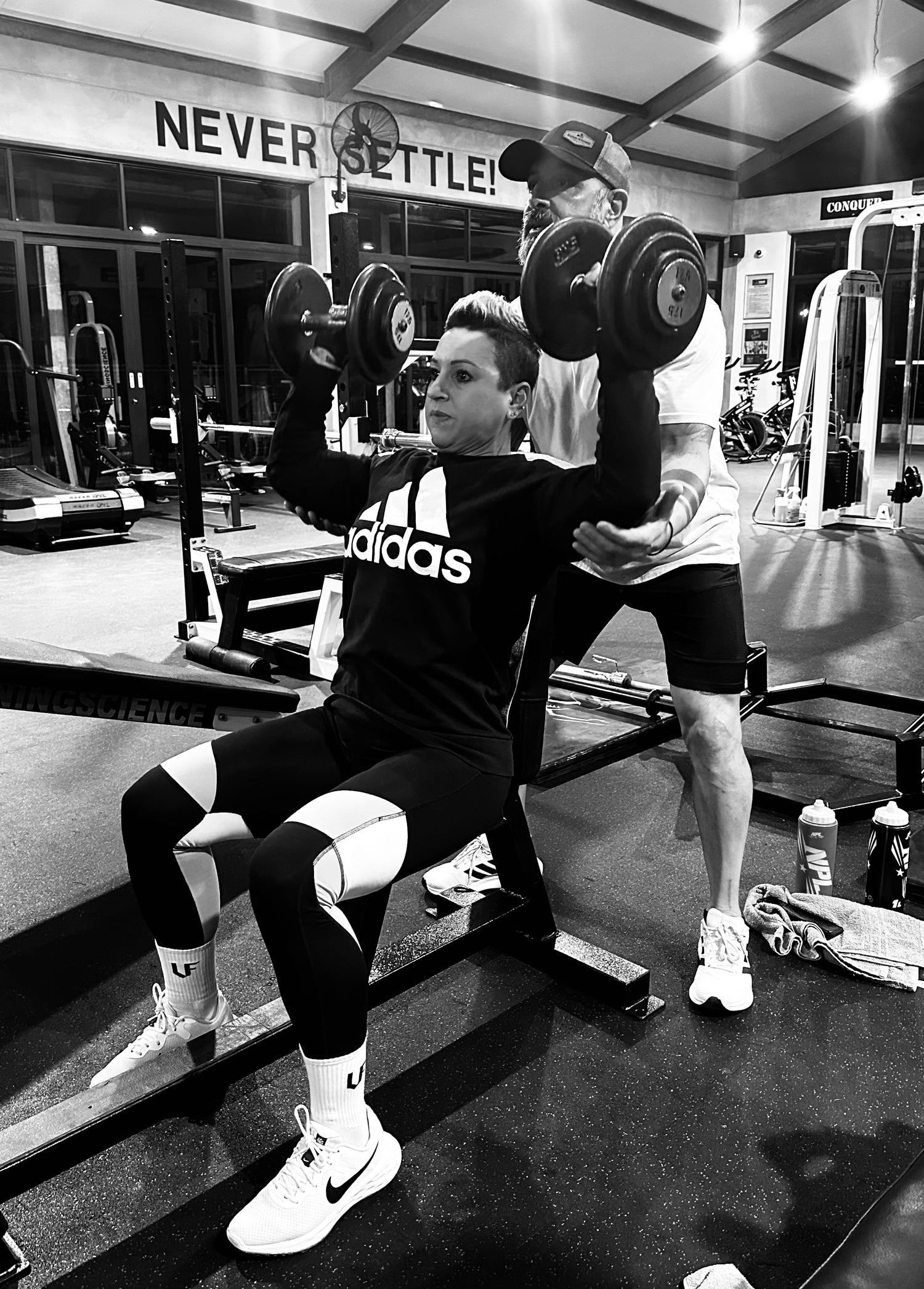 Person lifting weights in a gym with 'Adidas' branding visible