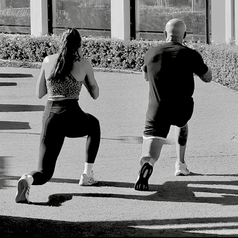 Two people performing a workout routine on a sidewalk.