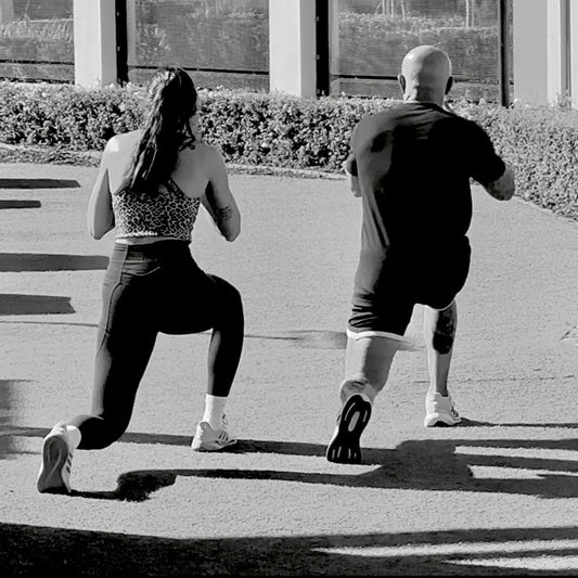 Two people performing a workout routine on a sidewalk.